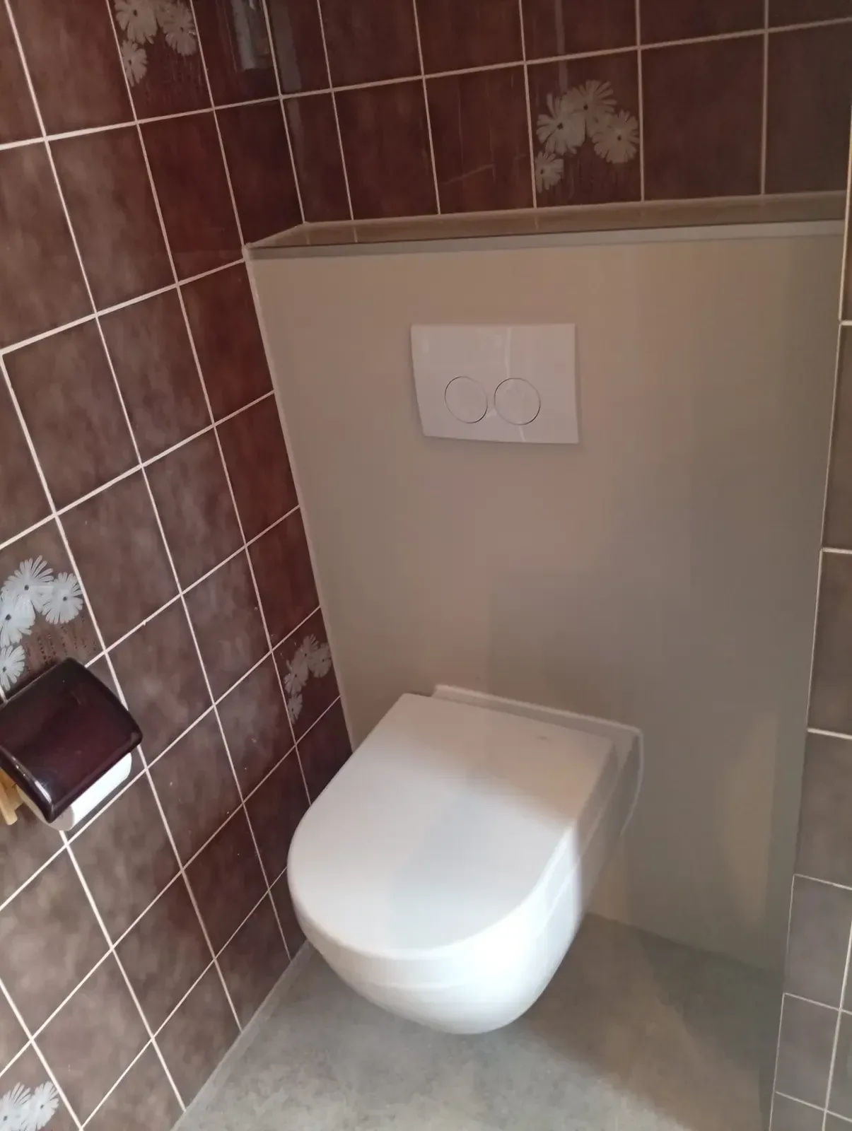 Hangtoilet op een nieuwe witte voorzetwand tussen bestaande bruine wandtegels