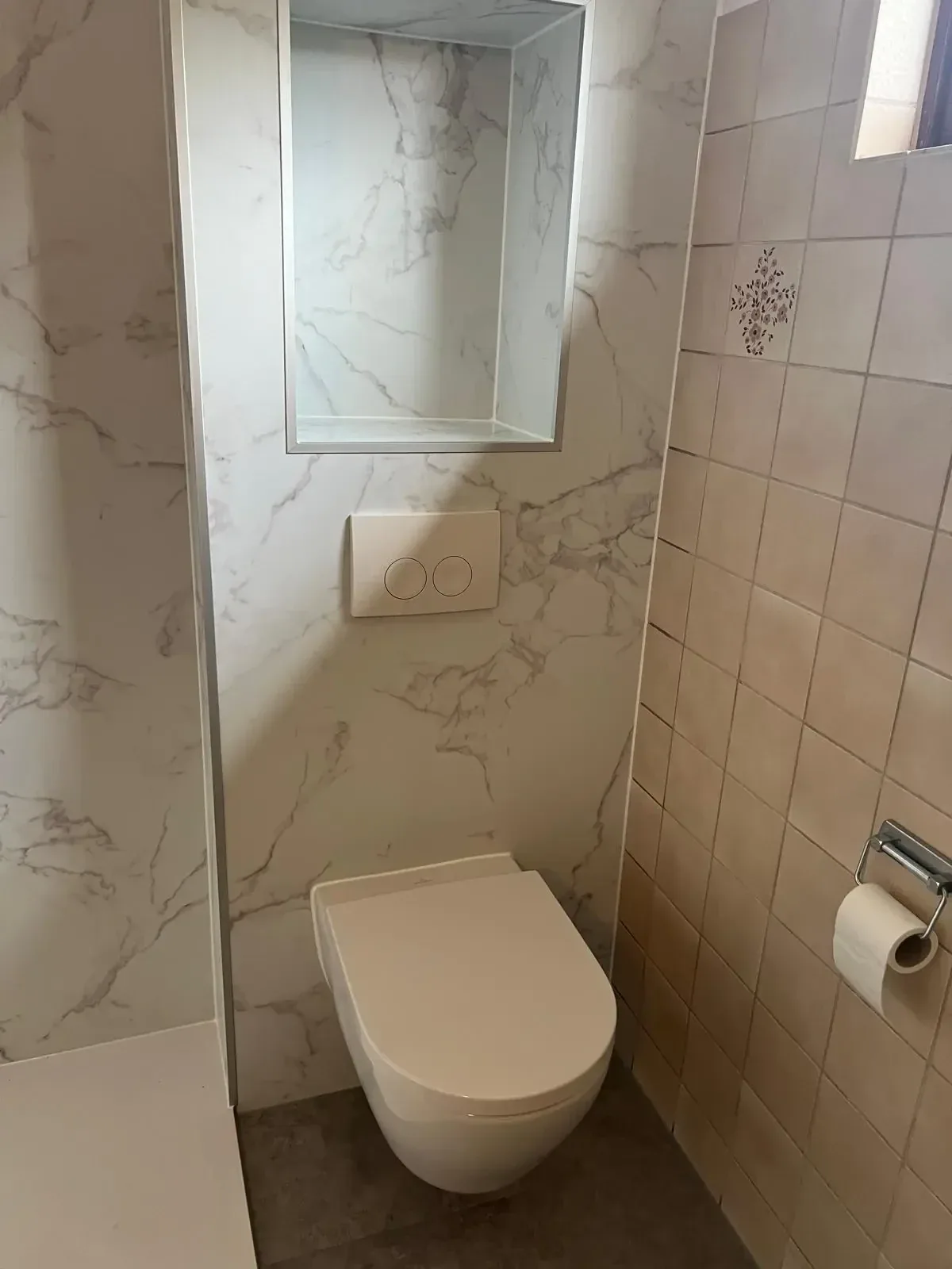 Hangtoilet op een voorzetwand met marmerlook panelen en een nis erboven