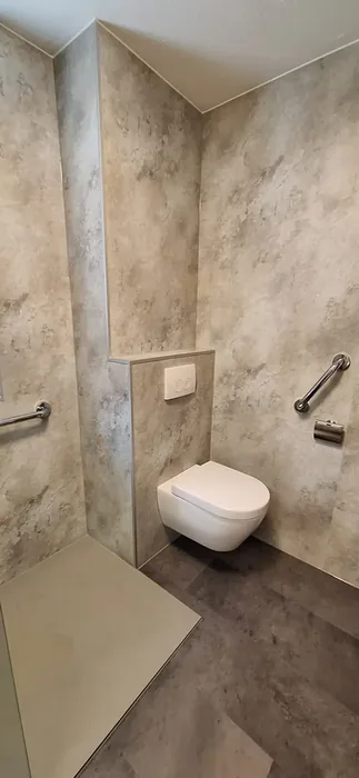 Hangtoilet op een voorzetwand met beige marmerlook panelen en steunbeugels aan beide kanten